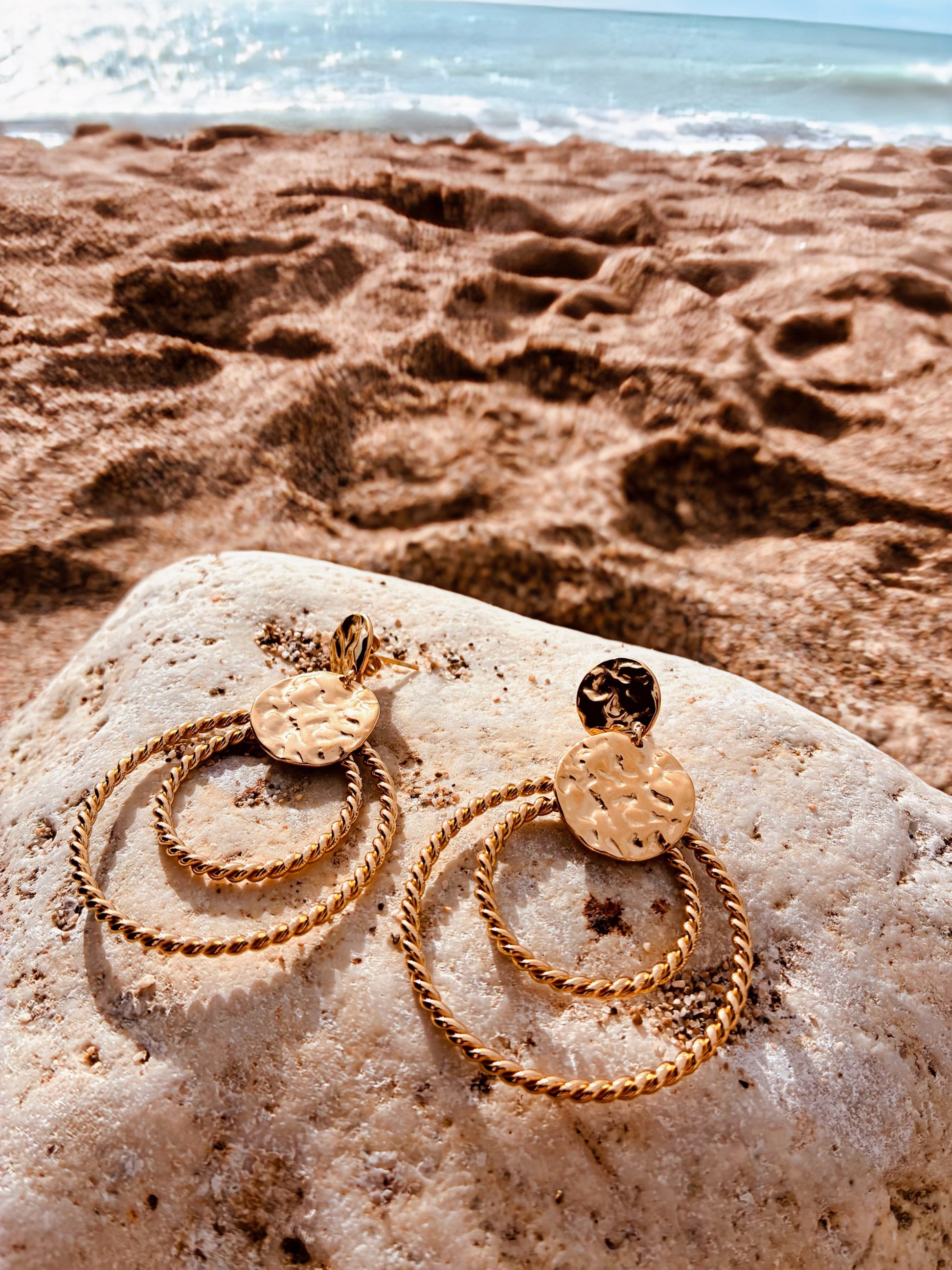 Boucles d’oreilles dorées femme Lina double anneau torsadé acier inoxydable sur galet plage