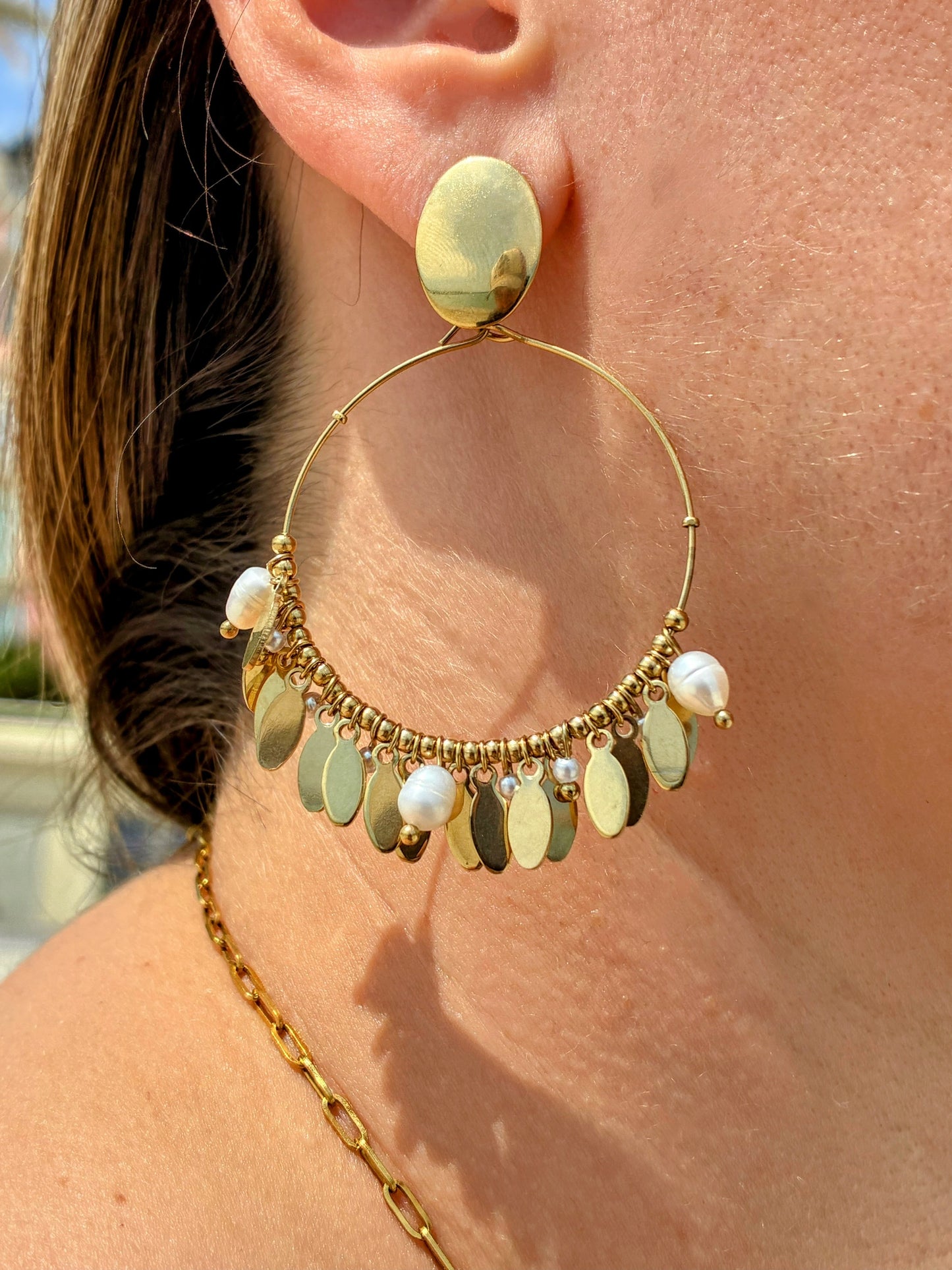 Boucles d’oreilles Alma dorées avec perles d’eau douce blanches portées au soleil